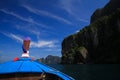 View on blue decorated wooden bow of longtail boat and rock wall under blue sky with few cirrus clouds Royalty Free Stock Photo