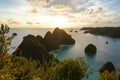 A view of the blue lagoon with a sunset sky, some sailing ships and limestone islands in remote archipelago.