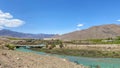 View of the blue mountain river and the bridge in the distance. Blue sky and white clouds. Beautiful summer mountain landscape. Royalty Free Stock Photo