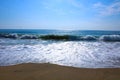 Blue ocean waves breaking on a sandy beach with blue skies