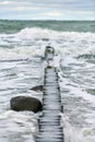 View of blue sea with foaming waves and wooden breakwaters Royalty Free Stock Photo