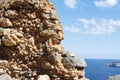 View of blue sea and sky from hole in old stonewall wall.