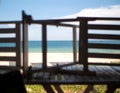 View of the blue sea and the yellow sandy beach overgrown with green grass, through a wooden trellis. Royalty Free Stock Photo