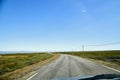 View on blue sky and grey road from the car front window in early mourning. Driving car during sunshine in the tundra in Norway. Royalty Free Stock Photo