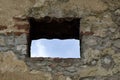 View of blue sky through square window of loophole in wall of an ancient fortress. Copy space