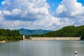 View of blue sky, white clouds and green hills and forest at outdoor reservoir Royalty Free Stock Photo