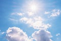 View of the blue sky with white cumulus clouds and the bright sun with rays and highlights