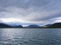 View from boat on Kaskajaure lake with colorful hills, mountains and birch trees forest.. Cloudy sky Royalty Free Stock Photo