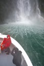 View from boat on Milford Sound, South Island, New Zealand. The front of the boat is taken very close to the waterfall.