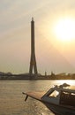 View of a boat in the river, the bridge tower and city on background under orange sky evening sunset, backlight photo Royalty Free Stock Photo