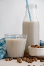 View of bottle with blue straw and glass with horchata and tiger nuts on white table