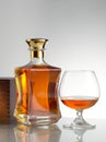 view of bottle of whiskey and a glass aside on grey back.