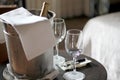 View of bottle of white rose wine in cooler and crystal glasses in room with armchairs and fireplace Royalty Free Stock Photo