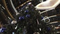 View from the bottom on the high Christmas fur tree decorated by blue and silver balls and garland of colorful lights Royalty Free Stock Photo