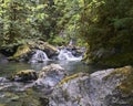 View of the boulders along the river's edge and the waterfall that tumbles through the lush bush. Royalty Free Stock Photo