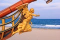 View of the bow and the figurehead of a stylized vintage sailboat close-up against the backdrop of the beach in Varna