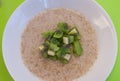 View of a bowl of porridge against green background with chopped kiwi fruit
