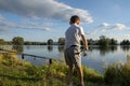 View on boy fishing on a lake from behind. Beautiful fish pond in Badin, near Banska Bystrica, Slovakia. Child holding fishing rod Royalty Free Stock Photo