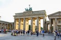 View of Brandenburg gate in summer with crowd of people. Quadriga statue on top and clouds in blue sunset sky backgro