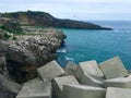 View of a breakwater formed by concrete cubes on a scenic coastline of mountains