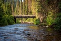 A view of a bridge across mountain river flowing through a forest at sunrise Royalty Free Stock Photo