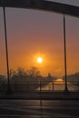 View through a bridge bow to a sunrise over a channel in Berlin on a misty morning with fairytale sunlight