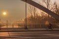 View through a bridge bow to a sunrise over a channel in Berlin on a misty morning with fairytale sunlight.