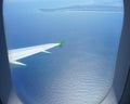 VIew of bright blue sea from an airplane window. Landscape coast, airplane wing. Rays of the sun on the water