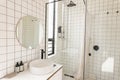 View of bright modern bathroom interior with white tiles and glass shower cabin Royalty Free Stock Photo