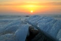 View of the broken melting ice cover of the Volga River against the backdrop of a magnificent sunset and clouds.