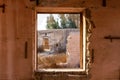View through a broken window of ruined buildings and courtyard in Al Jazirah Al Hamra, UAE