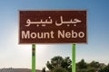 View of a brown wooden sign bearing the announcement of Mount Nebo with white letters. The place in Jordan, where Moses got a view