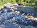 View of the bubbling waterfall with brown water on the Tokhmayoki River in Karelia from the ecological trail