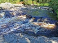 View of the bubbling waterfall with brown water on the Tokhmayoki River in Karelia from the ecological trail