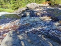 View of the bubbling waterfall with brown water on the Tokhmayoki River in Karelia from the ecological trail