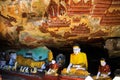 View into buddhist cave with colorful buddha statues and mural paintings