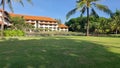 View of the building along with a stretch of green planting with a coconut tree