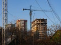 A view of a building that is under construction with a crane near it against blue sky. In the foreground there is a tall metal Royalty Free Stock Photo