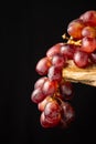 View of bunch of wet black grapes on rustic wooden table, black background Royalty Free Stock Photo