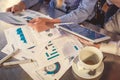 View of business people, sitting at the table and pointing handles on the chart and on tablet