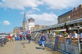 View on busy rhine river promenade with people sitting outside restaurant on sunny spring day