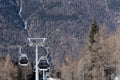 View of the cable car with skiers against the backdrop of the mountains on a slope in early spring. Royalty Free Stock Photo