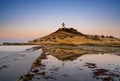 view of the Cabo de la Huerta lighthouse at sunrise with reflections in tidal pools in the foreground Royalty Free Stock Photo