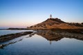 view of the Cabo de la Huerta lighthouse at sunrise with reflections in tidal pools in the foreground Royalty Free Stock Photo