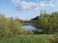 View on calm water of forest lake, fish pond Kunraticky rybnik with birch and spruce trees growing along the shore and Royalty Free Stock Photo