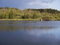 View on calm water of forest lake, fish pond Kunraticky rybnik with dam pier, birch and spruce trees growing along the Royalty Free Stock Photo