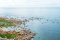 View of the cape on the coast with a meadow and a scattering of stones on the shore of the northern sea.