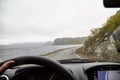 View from the car window of sad, harsh, dramatic landscape with a lake, river or fjord, a rock in the distance on the horizon and Royalty Free Stock Photo