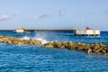 View of the Caribbean Sea with a pier and an artificial breakwater where waves crash against the rocks. Royalty Free Stock Photo