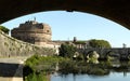 View of Castel Sant`Angelo from a bank of the Tiber river, framed by the shadow of a bridge